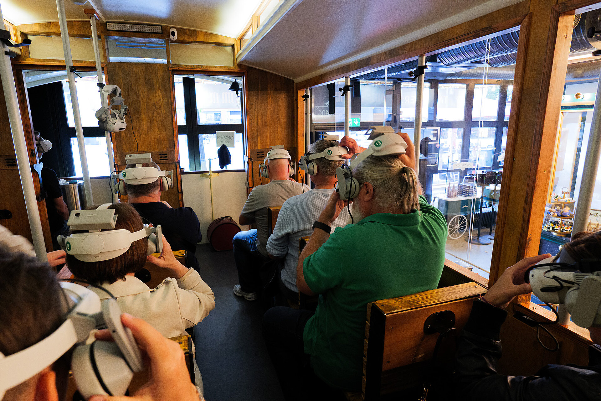 Teilnehmer des audatis MANAGER User-Forums sitzen in euner historischen Straßenbahn und setzen VR-Brillen auf