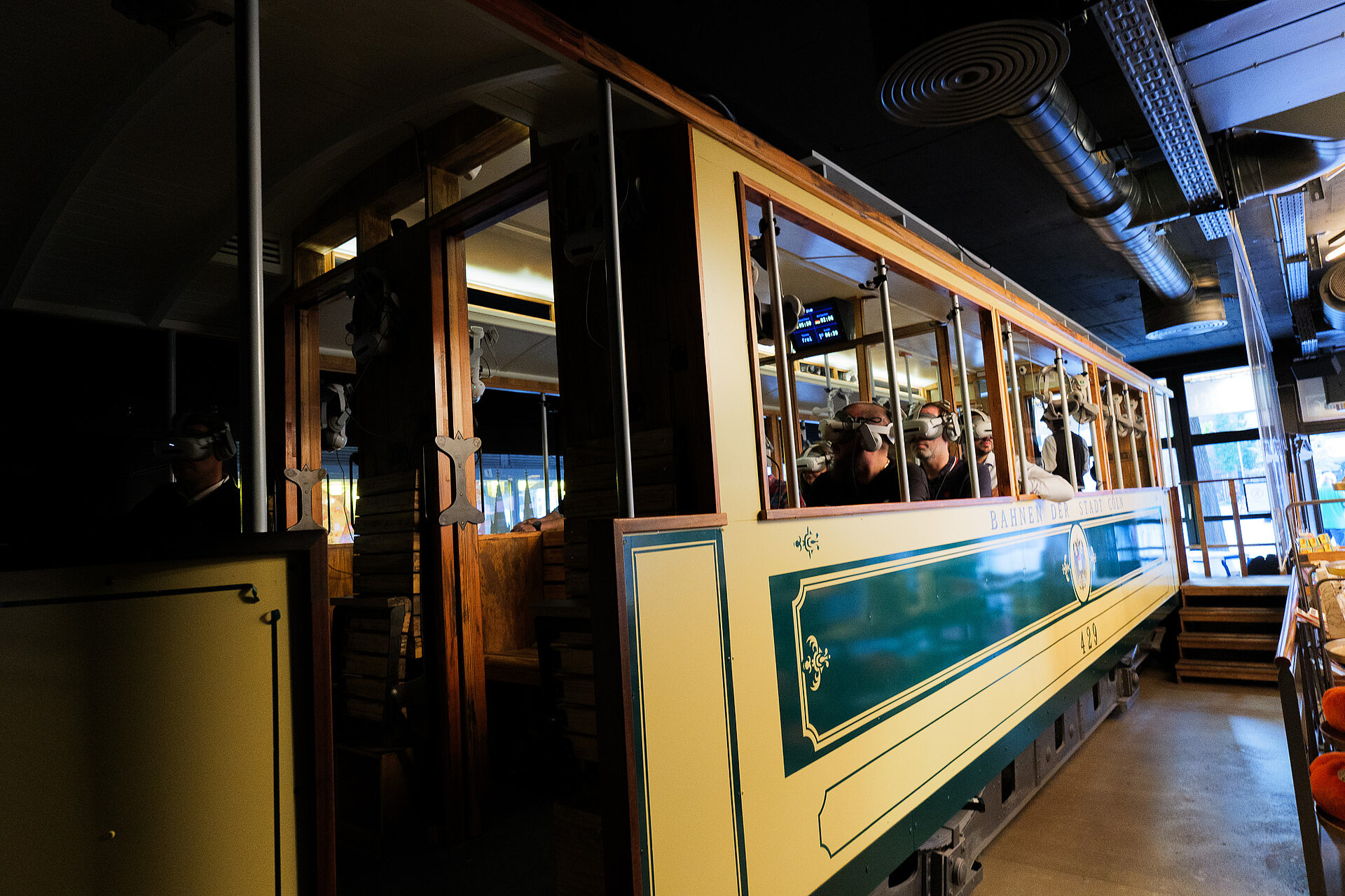 Teilnehmer des audatis MANAGER User-Forums sitzen mit VR-Brillen in einer historischen Straßenbahn