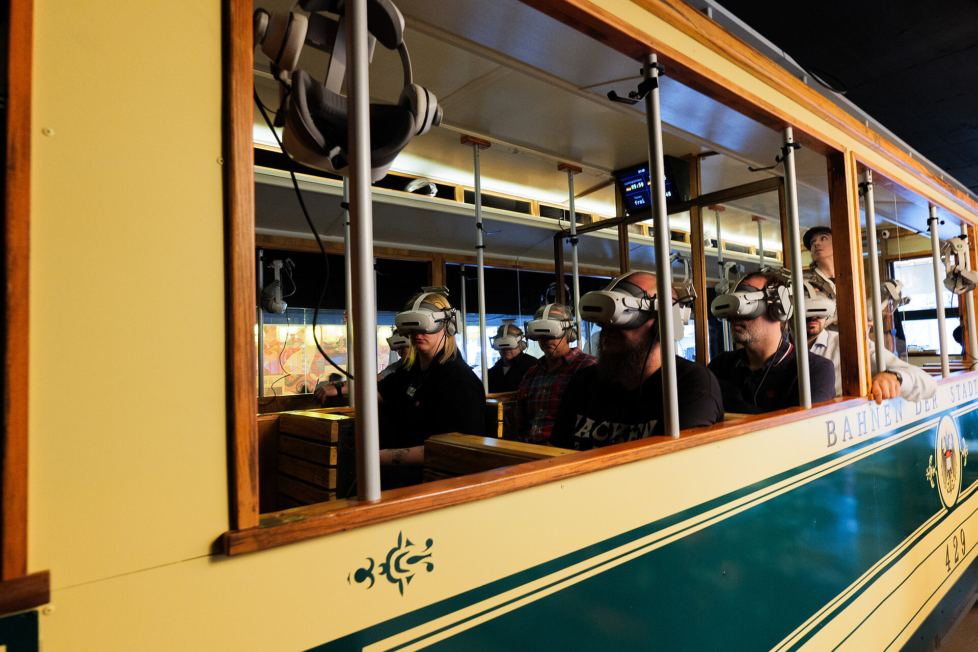 Teilnehmer des audatis MANAGER User-Forums sitzen mit VR-Brillen in einer historischen Straßenbahn